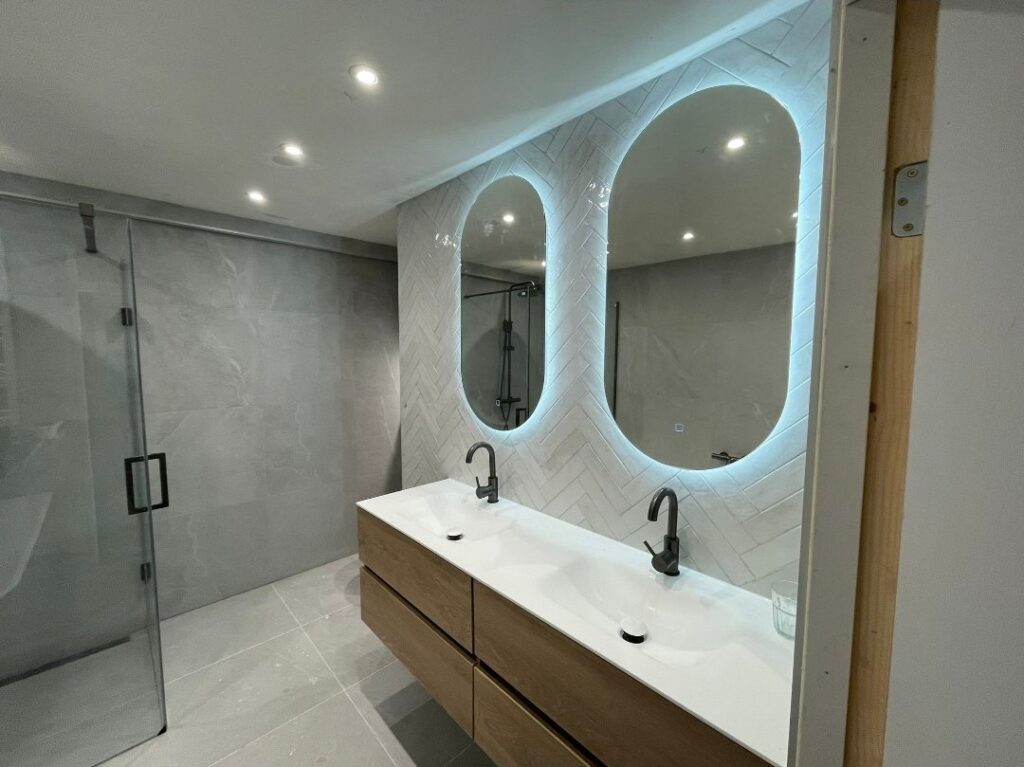 Moderne badkamer renovatie met witte tegels en glazen douche in Rotterdam