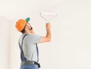 Binnenschilder aan het werk met witte muurverf in woonhuis